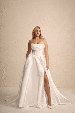 Bride posing sideways in strapless A-line wedding dress with slit